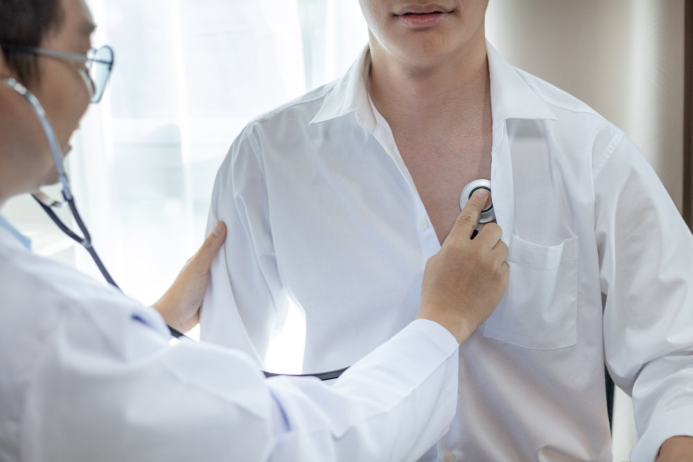 Badanie osłuchowe klatki piersiowej stetoskopem u osoby w białej koszuli – diagnostyka układu oddechowego i sercowo-naczyniowego.