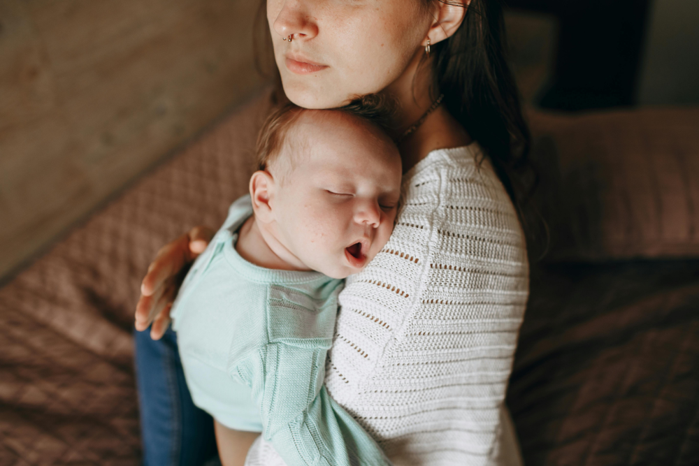 Opiekun trzymający niemowlę na rękach w domowym wnętrzu, dziecko ubrane w jasne ubranko