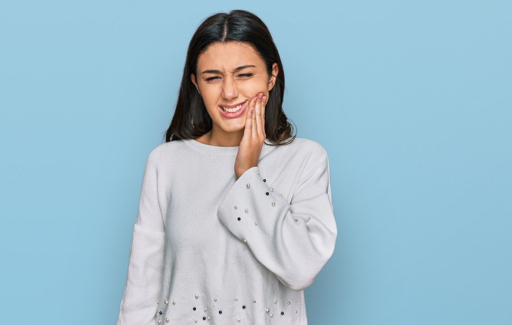 Young hispanic girl wearing casual clothes touching mouth with hand with painful expression because of toothache 