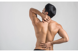 Osoba stojąca tyłem z odkrytymi plecami, jedną dłonią podtrzymująca dolny odcinek kręgosłupa, drugą sięgająca do górnej części pleców