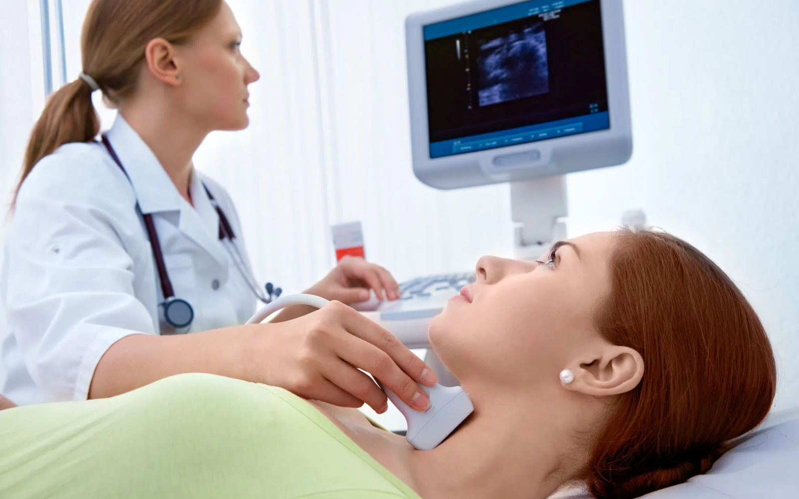 Badanie USG tarczycy wykonywane w gabinecie lekarskim, głowica ultrasonograficzna przykładana do szyi pacjenta, obraz przedstawiający diagnostykę chorób tarczycy, w tym Hashimoto, niedoczynności tarczycy oraz zmian w obrębie gruczołu tarczowego.